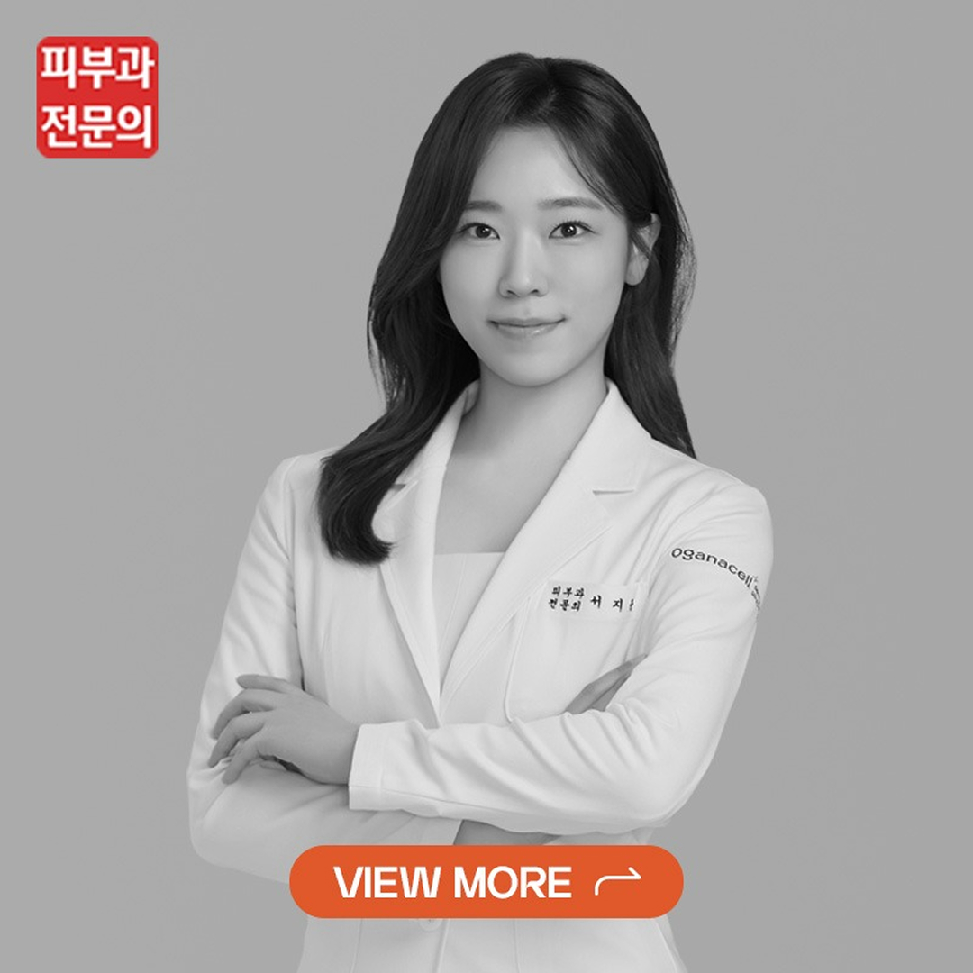Professional portrait of a smiling woman in a white coat with arms crossed and an orange 'VIEW MORE' button overlay at the bottom.
