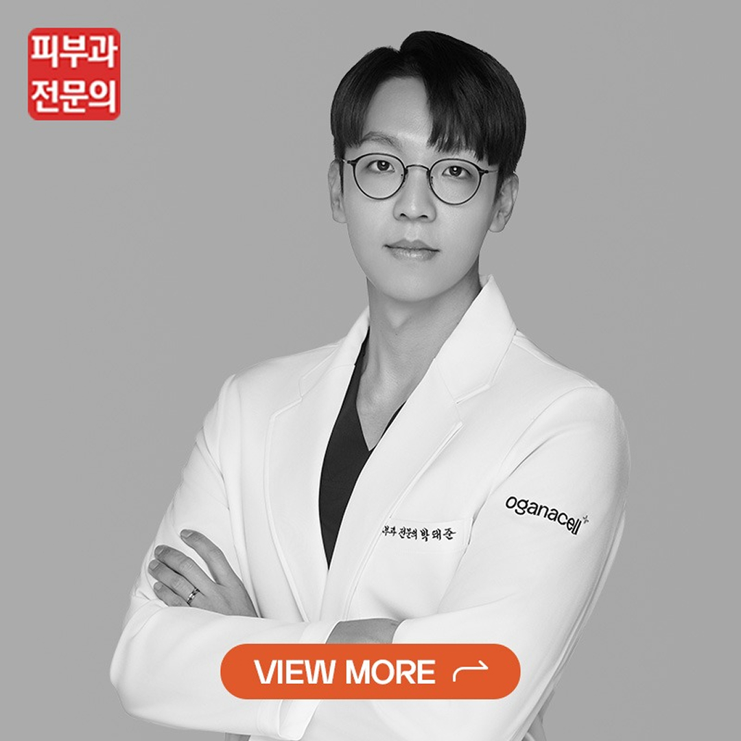 Black-and-white portrait of a clinician with glasses in a white coat, arms crossed, with an orange 'VIEW MORE' button overlay.