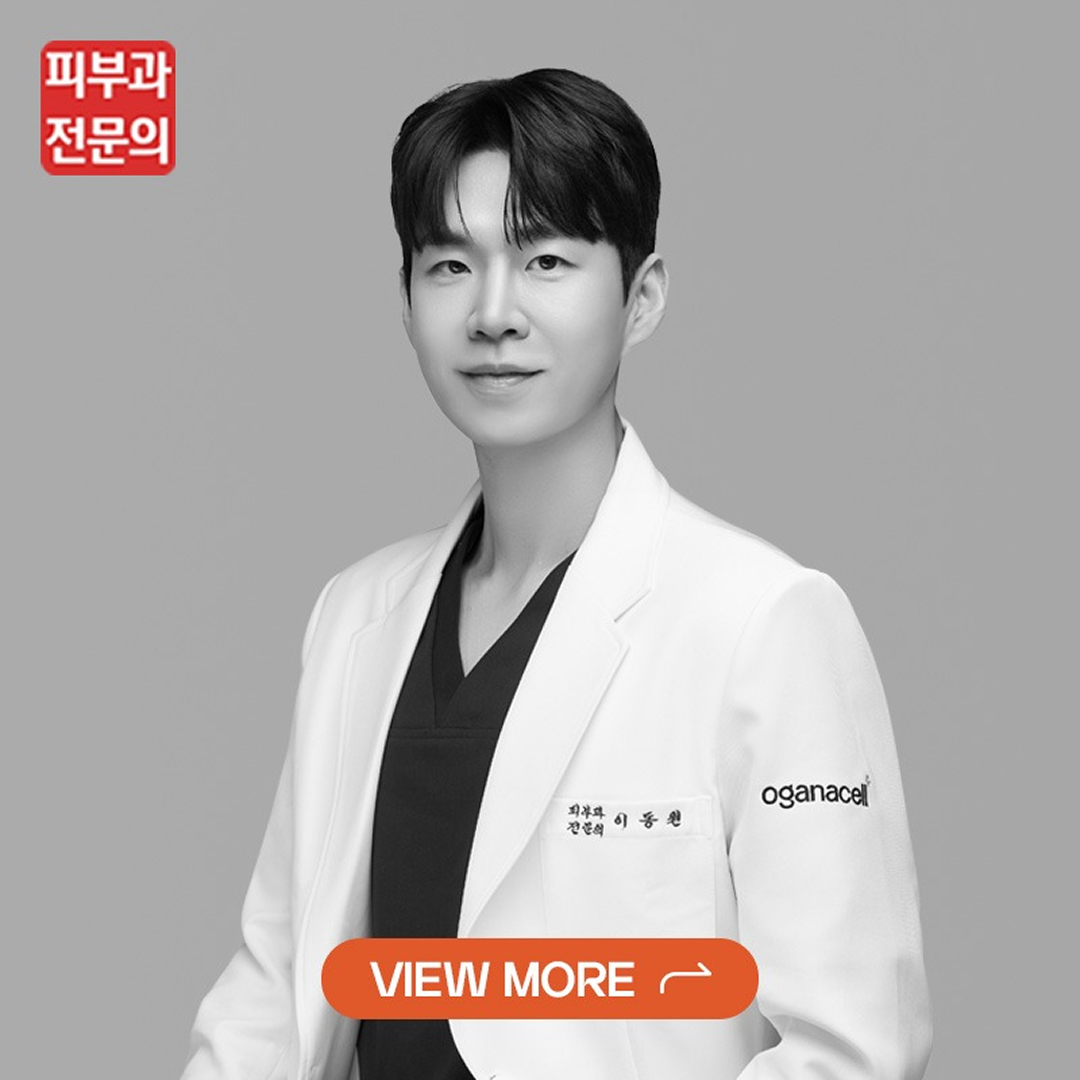 Portrait of a medical professional in a white coat against a gray background, looking at the camera